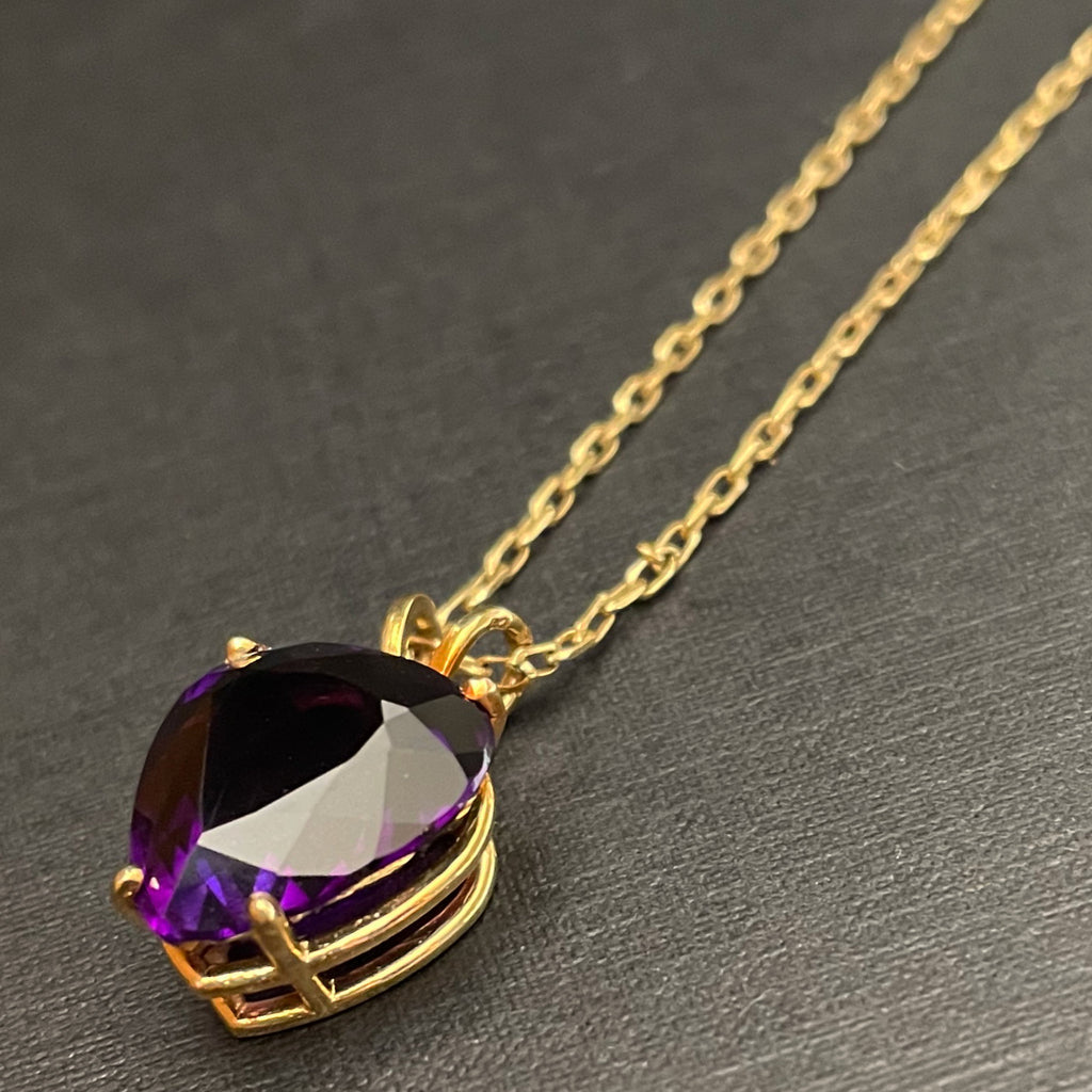 Large plum deep purple amethyst pendant in the shape of a heart on a gold chain. 