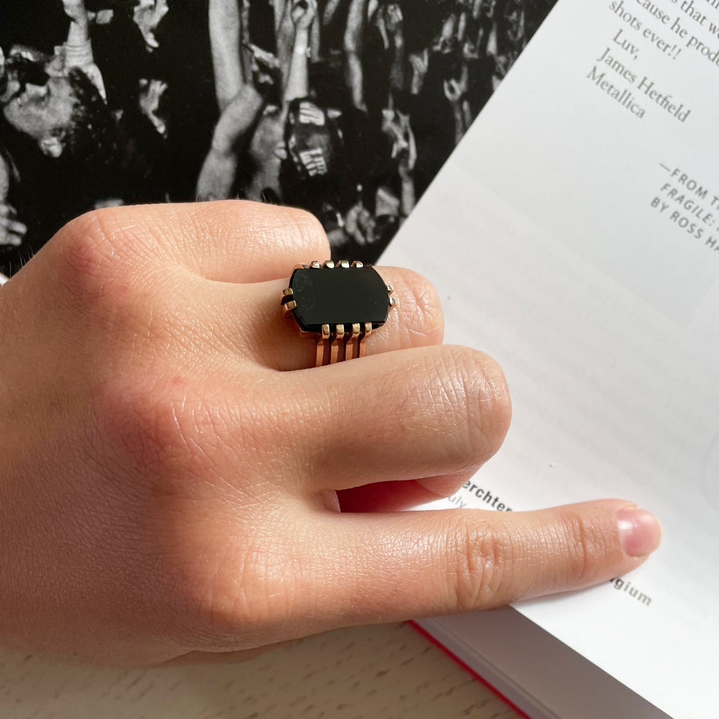 A woman's hand wearing a black opal ring set in gold.