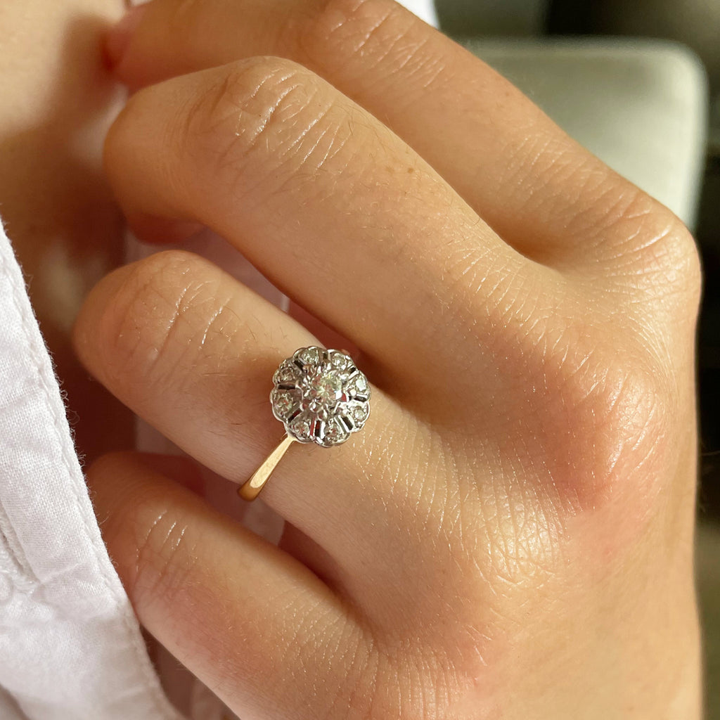 Diamond cluster ring on woman's hand with white shirt.