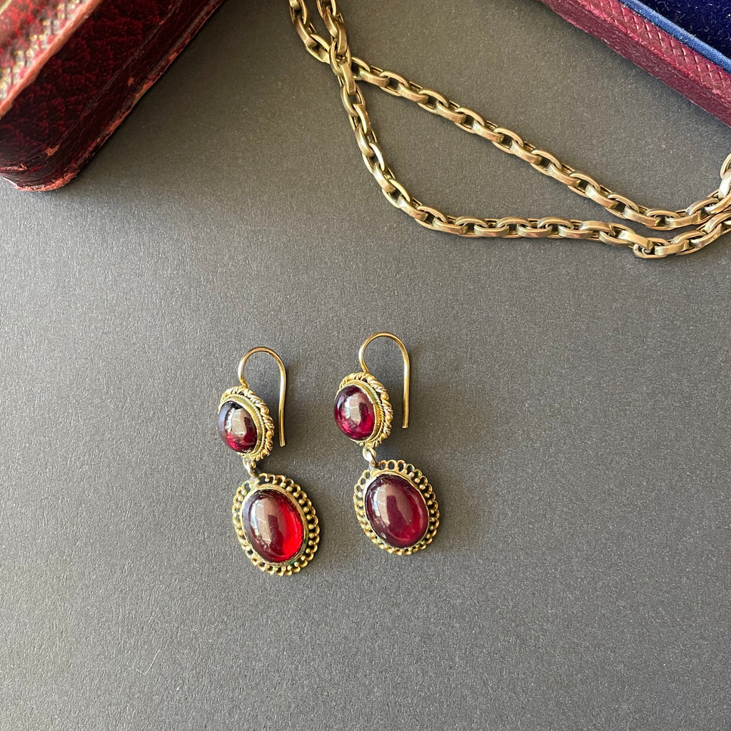 Gold earrings with large oval cabochon garnet drops.