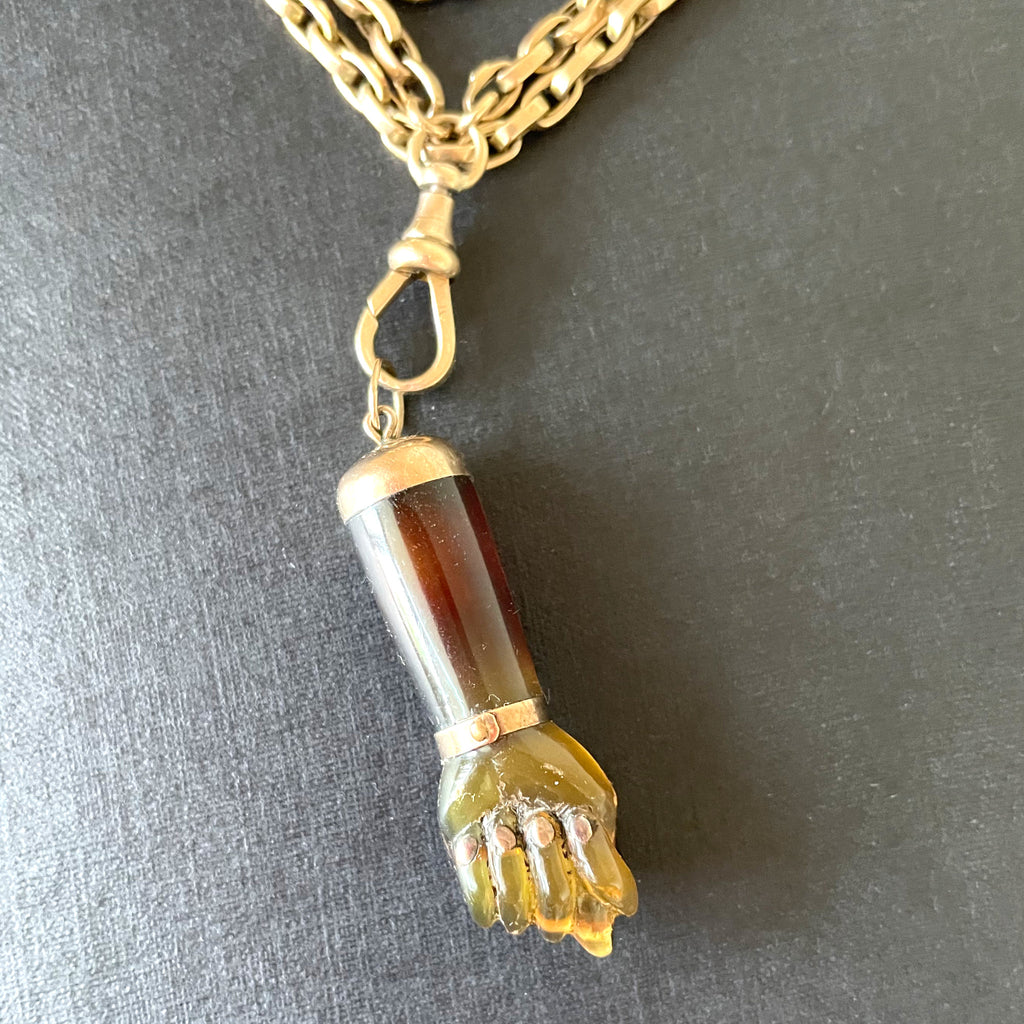 Figa pendant made of tortoiseshell on a gold long guard chain.