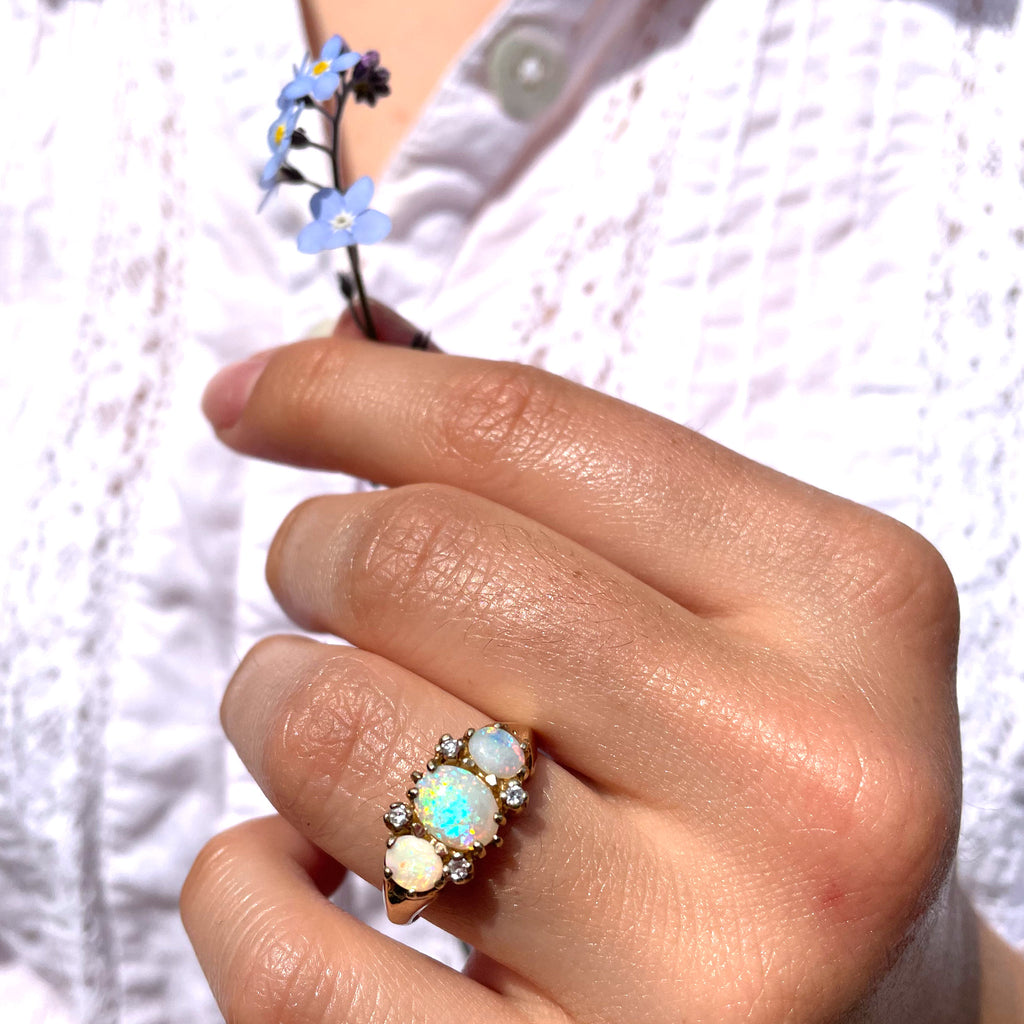 An opal ring displaying various colours and woman holding flowers.