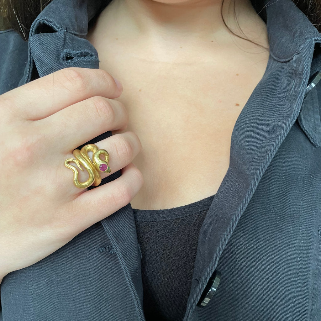 woman wears gold snake ring with rubies and black jacket