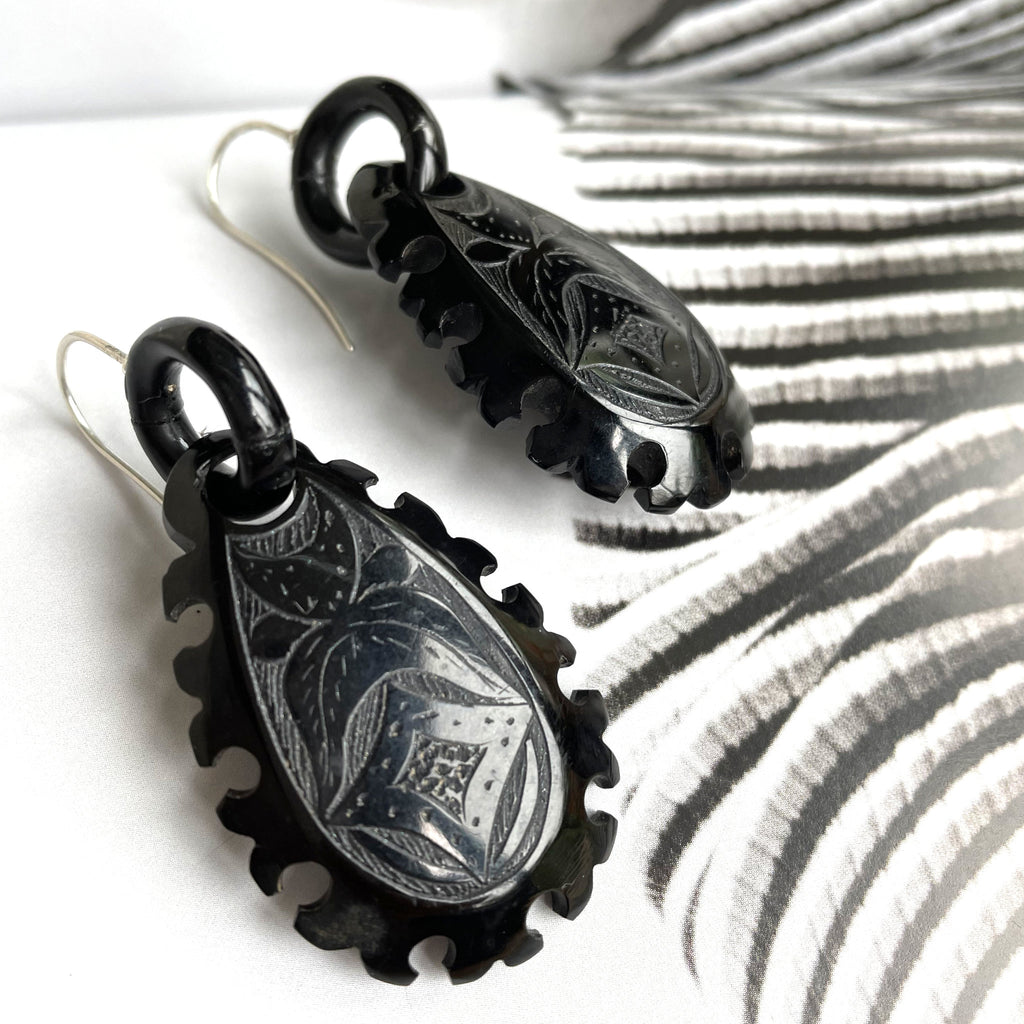 Large whitby jet earrings with geometric designs around edges and etched flowers in middle.