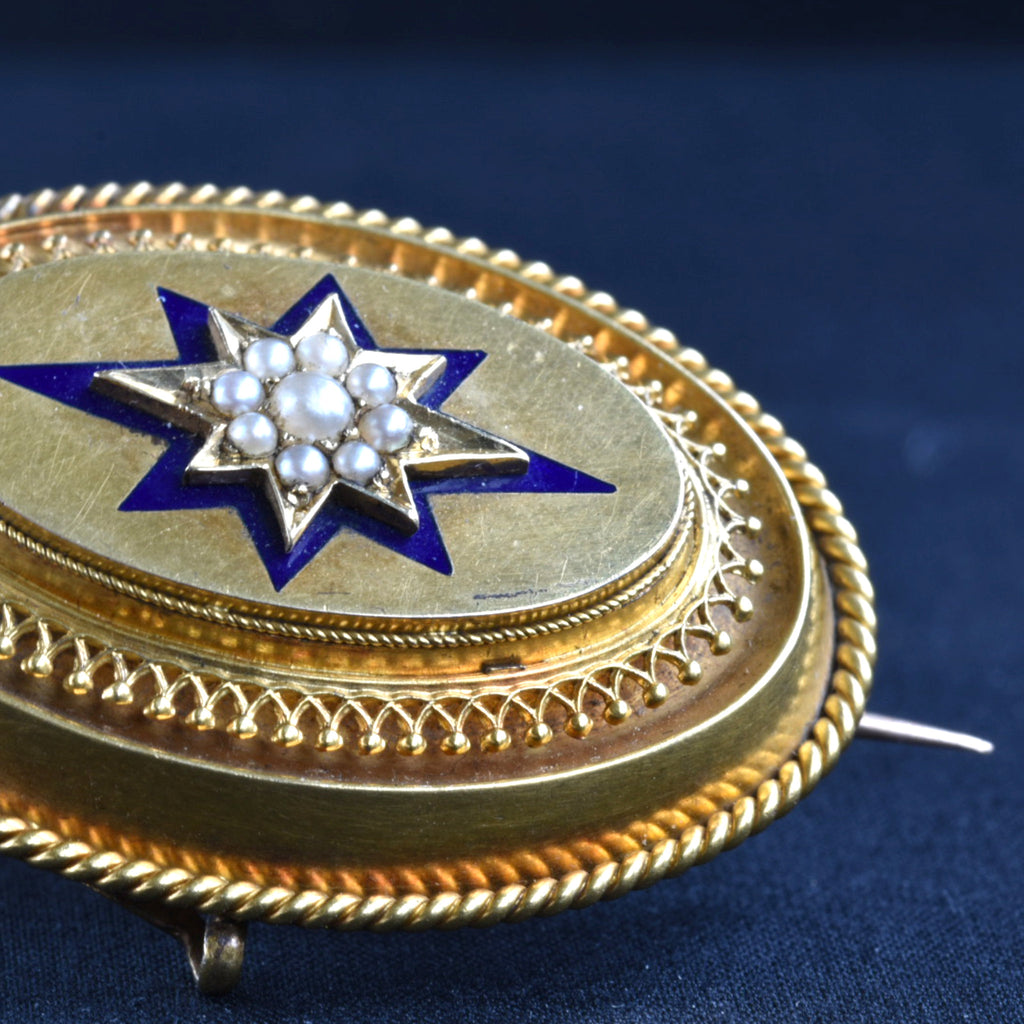 Gold locket with blue enamel star and pearls on dark blue background.