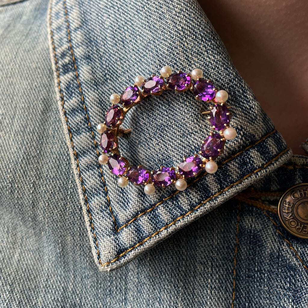 Bright purple amethyst brooch with pearls on denim jacket.