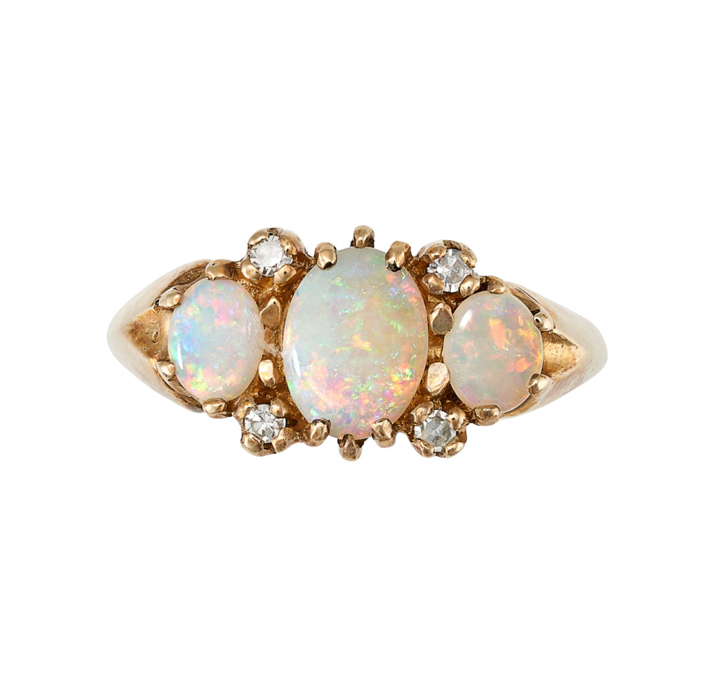A gold ring with three opal cabochons and four diamond shoulders.